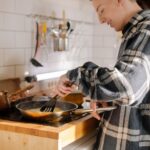 Student w kraciastej koszuli gotuje prosty posiłek w nowoczesnej kuchni