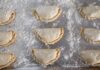 Kuchnia latynoamerykańska zero-waste: jak zrobić empanady i enchilady z resztek obiadu Surowe empanady na oprószonej mąką blasze przed pieczeniem