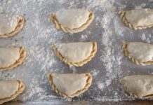 Kuchnia latynoamerykańska zero-waste: jak zrobić empanady i enchilady z resztek obiadu Surowe empanady na oprószonej mąką blasze przed pieczeniem